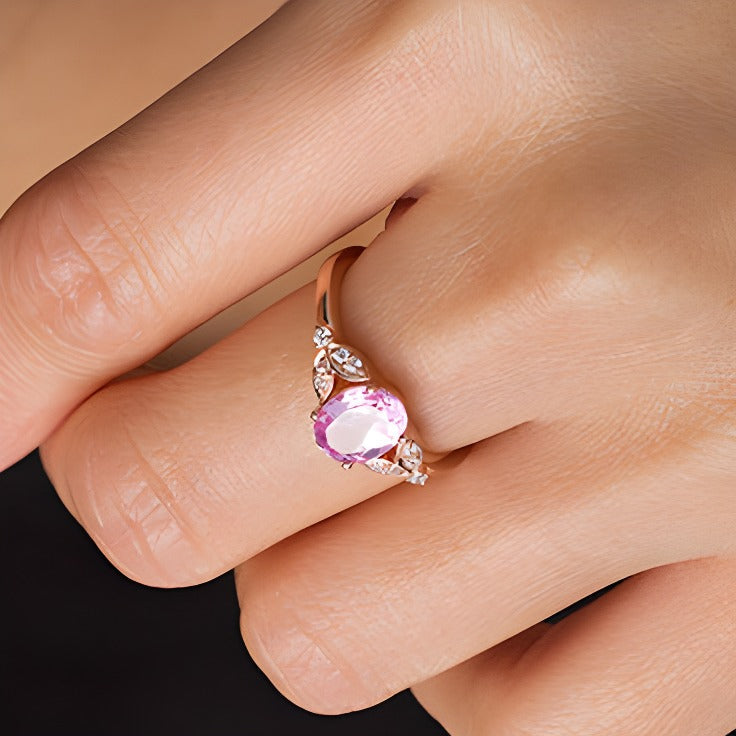 Ring mit ovalem im Labor gezüchteten rosa Saphir und 0,1 ct. Gesamtgewicht Diamanten mit Blattmotiv-Seiten in 10K Roségold